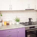 Kitchen purple, lavender color, white cabinets, green flowers, black oven.
