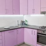 Contemporary kitchen with pastel purple cabinets, stainless steel appliances, gas stove, and under-cabinet lighting in a corner layout.